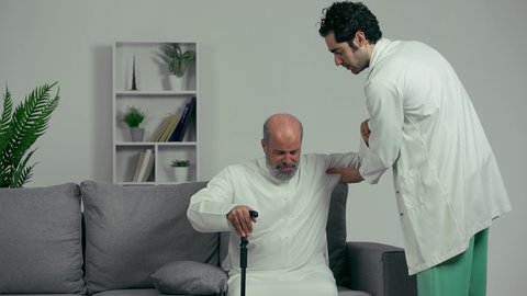طبيب اماراتي  يقوم بتمشيه رجل مسن للتأكد من سلامته رجله من الكسر، رجل مسن يشتكي من ألم خشونه الركبه، مفهوم المساعده لكبارالسن