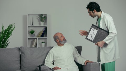 نتائج الفحوصات والتحاليل المرضيه، رجل مسن يرتدي كندوره يقوم بالدعاء والشكر، نتائج تحاليل و أشعة إيجابية, طبيب عربي خليجي اماراتي يرتدي المعطف وسماعه الفحص الطبيه يحمل دفتر سجلات المرضى بيده يقوم بطمأنة المريض
