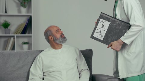 نتائج الفحوصات والتحاليل المرضيه، رجل مسن يرتدي كندوره يقوم بالدعاء والشكر، نتائج تحاليل و أشعة إيجابية, طبيب عربي خليجي اماراتي يرتدي المعطف وسماعه الفحص الطبيه يحمل دفتر سجلات المرضى بيده يقوم بطمأنة المريض