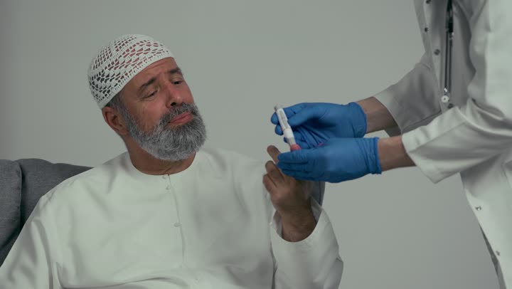 طبيب عربي خليجي اماراتي يقوم بفحص مريض كبير بالسن يعاني من داء السكري، مشاكل ارتفاع وانخفاض السكر في الدم، جهاز قياس السكر في الدم خاص لمرضى السكري، مفهوم الطب والرعاية الطبية، مهن ووظائف طبية، رجل مسن يعاني من ارتفاع السكر في الدم