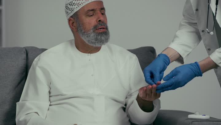طبيب عربي خليجي اماراتي يقوم بفحص مريض كبير بالسن يعاني من داء السكري، مشاكل ارتفاع وانخفاض السكر في الدم، جهاز قياس السكر في الدم خاص لمرضى السكري، مفهوم الطب والرعاية الطبية، مهن ووظائف طبية، رجل مسن يعاني من ارتفاع السكر في الدم