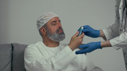 ادوية لمعالجة الحالات المرضية والوقاية من امراض التنفس، صورة مقربة لطبيب عربي خليجي اماراتي يرتدي المعطف الابيض يمسك بيده جهاز الرذاذ الخاص بمرض الربو، رجل مسن يعاني من مشاكل صحية في التنفس، أجهزة استنشاق المخصصة لمرضى الربو، مشاكل صحية