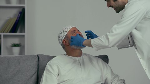استخدام معدات وأدوات طب الأسنان، زيارة العيادات الصحية وإتخاذ الإجراءات اللازمة، الأساليب العلاجية المتبعة للعناية بالفم، معالجة التسوس وتركيب الحشوات،  طبيب عربي خليجي اماراتي يرتدي القفازات يقوم بفحص أسنان الرجل المسن