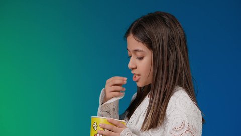 الاشاره الى موقع معين ،ايماءات الاستمتاع بمشاهدة فيلم ممتع،الابتعاد عن روتين الحياة اليومية،  متابعة الأفلام والعروض المسرحية في السينما، تصوير لبنت عربية خليجية اماراتيه مبتسمة ترتدي الزي الكاجوال ونظاره سوداء تمسك بيدها علبه الفوشار ، خلفية ملونه