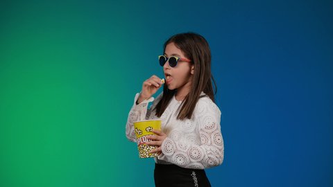 الاشاره باصبع السبابه الى شئ ما ، متابعة الأفلام والعروض المسرحية في السينما، الابتعاد عن روتين الحياة اليومية، بورتريه لبنت عربية خليجية اماراتيه مبتسمة ترتدي الزي الكاجوال ونظاره سوداء تمسك بيدها علبه الفوشار ، ايماءات الاستمتاع بمشاهدة فيلم ممتع، خلفية ملونه