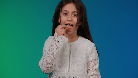 استخدام التقنيات الحديثة للتسلية والترفيه،قضاء اوقات ممتعة باللعب ، تصوير لبنت عربية خليجية اماراتيه مبتسمة ترتدي الزي الكاجوال تجلس على اريكة رمادية تقوم باللعب في ألعاب الفيديو بتعابير وايماءات الاندماج والتركيز، خلفية ملونه