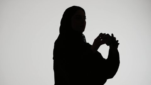Professional Emirati photographer, taking commemorative photos, silhouette of an Arab Gulf Emirati woman wearing an abaya and hijab, holding a high-resolution camera, mastering the photography profession, white background