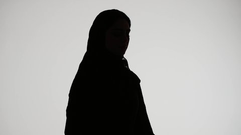 Writing research and reports, silhouette of an Emirati Gulf Arab woman wearing an abaya and hijab, holding work papers, reading notes and information, concept of education and culture, following up on plans and projects, white background