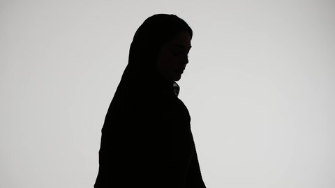 Following up on plans and projects, reading notes and information, the concept of education and culture, writing research and reports, a silhouette of an Arab Gulf Emirati woman wearing an abaya and hijab, holding work papers, white background