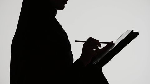 إستخدام اجهزة تقنية حديثة ،دمج التكنولوجيا الحديثه فى الحياه اليوميه ، وسائل التواصل الإجتماعي ،انجاز مهام العمل بإستخدام التابلت ، اجراء مكالمه هاتفيه ،تصوير ظلي لمرأة عربية خليجية اماراتيه ترتدي العباءه والحجاب تمسك بيدها جهاز التابلت والقلم ، خلفية بيضاء