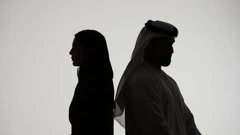 The concept of elegance and attention to one's outward appearance, intimacy and affection between spouses, silhouette of an Arab Gulf Emirati couple, standing straight with crossed arms, looking to the side, white background