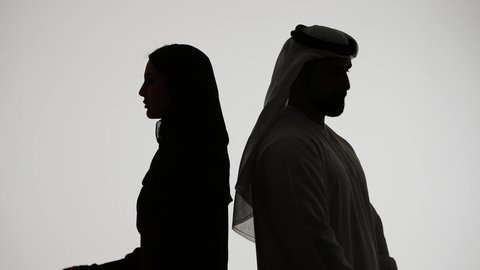 الالفه والموده بين الازواج، تصوير ظلي لزوجان عربيان خليجيان اماراتي، يقفان بإستقامة وإيدي متقاطعة ، ينظران إلى الجانب ، مفهوم الاناقه والاهتمام بالمظهر الخارجي ، خلفية بيضاء