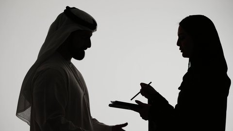 Business organization and management, taking notes and recording information on paper. Silhouette of an Emirati Gulf Arab woman writing down daily tasks and goals, white background.
