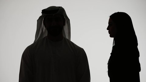 ايماءات الانصات والتركيز بالكلام،  النميمة والتحدث عن شخص ما، التحدث بصوت منخفض، تصوير ظلي لامراه عربيه خليجيه اماراتيه ترتدي العباءه والحجاب تهمس بإذن زوجها، مفهوم الكتمان وحفظ الأسرار بين الشقيقات، خلفية بيضاء