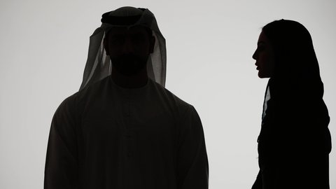 النميمة والتحدث عن شخص ما، ايماءات الانصات والتركيز بالكلام، التحدث بصوت منخفض، تصوير ظلي لامراه عربيه خليجيه اماراتيه ترتدي العباءه والحجاب تهمس بإذن زوجها، مفهوم الكتمان وحفظ الأسرار بين الشقيقات، خلفية بيضاء