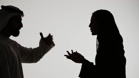 دفاع المرأة عن نفسها،  شجار بين الزوجين،رجل إماراتي يرتدي الغترة والكندورة يقوم بضرب وتعنيف زوجته على وجهها، مشاكل عائلية وصراع اسري، ازمة في العلاقات الاسرية، تصوير ظلي لزوجين عربيين خليجيين اماراتيين يتجادلان مع بعضهما بإيماءات الغضب، خلفية بيضاء