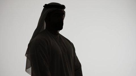 Contemplation and planning for the future, finding a solution to a problem, a side-view silhouette of an Emirati Gulf Arab man with his hand on his chin, looking at a place with gestures of thought and concentration, expressions of absent-mindedness and contemplation, white background
