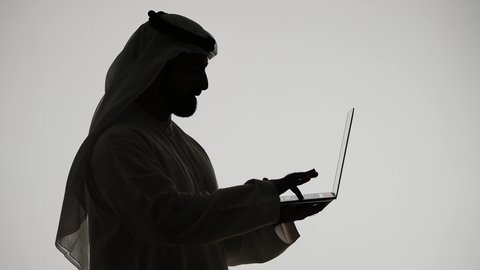 E-marketing concept, browsing social media, using a laptop, integrating modern technologies into daily life, silhouette of an Arab Gulf Emirati man, using modern technology devices, working remotely, Emirati jobs and professions, white background