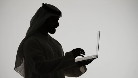 تصفح مواقع التواصل الاجتماعي ، إستخدام جهاز الحاسوب المحمول ،دمج التقنيات الحديثه فى الحياه اليوميه ، تصوير ظلي لرجل عربي خليجي اماراتي ،إستخدام اجهزة تكنولوجيا حديثة ، العمل عن بعد ، مفهوم التسويق الإلكتروني ، مهن ووظائف اماراتيه ، خلفية بيضاء