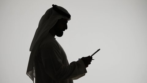 Online shopping using a tablet, completing tasks remotely, integrating modern technologies into daily life, silhouette of an Arab Gulf Emirati man, Emirati jobs and professions, white background