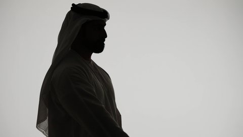 إشارات وحركات يدين تدل على هذا المكان (هنا)، تحديد موقع معين، النظر الى شيء ما ، تصوير ظلي لرجل عربي خليجي اماراتي يشير بأصابعه الى هدف محدد، خلفية بيضاء