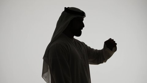 تصوير ظلي لرجل عربي خليجي اماراتي يقوب بشرب المياه من عبوة بلاستيكية، التخلص من سموم الجسم، المحافظة على سلامة الجهاز المناعي، أهمية شرب الماء النقي للمحافظة على بشرة نضرة، خلفية بيضاء