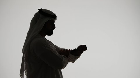 Schedule management, silhouette of an Emirati Gulf Arab man wearing a wristwatch, looking at it, keeping track of time, scheduling work, organizing and arranging time, white background