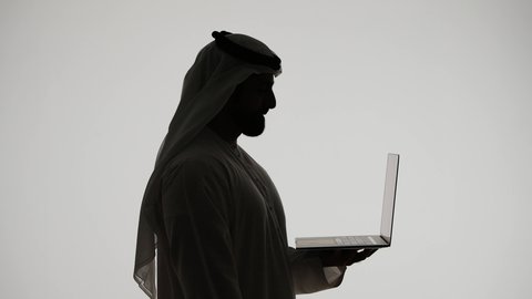 Browsing social media, using a laptop, silhouette of an Emirati Gulf Arab man, using modern technology devices, working remotely, the concept of electronic marketing, Emirati professions and jobs, white background