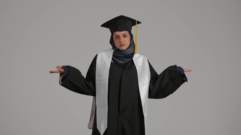إنهاء الدراسة الجامعية، مفهوم الحيره ، تعابير الجهل وعدم معرفه شئ ما، تحقيق حلم النجاح, الاحتفال بالتخرج من الجامعة، مفهوم الاجتهاد والتفوق ، بورترية لطالبة عربية خليجية اماراتيه محجبة ترتدي روب التخرج والقبعة، خلفية رمادية