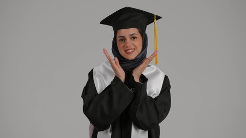 ايماءات وجه ويدين تدل على السعادة بالتفوق والنجاح، المناسبات والاحتفالات الجامعية,بورتريه مقرب لطالبة جامعية خريجة عربية اماراتية خليجية تلبس قبعة التخرج , تلميذه متفوقه, مدارس وجامعات, التعليم في الامارات العربية , خلفية رمادية
