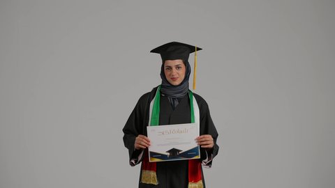 مفهوم الدراسة والنجاح والتفوق، إيماءات الفرح والسرور, بورترية لطالبة عربيه خليجيه اماراتية ترتدي العباءه وقبعة التخرج تحمل بيده شهادة النجاح، بنت سعودية تحتفل بإنهاء الدراسة الجامعية، الاهتمام بالأناقة والمظهر الخارجي, مفهوم الاجتهاد والتفوق، خلفية رمادية