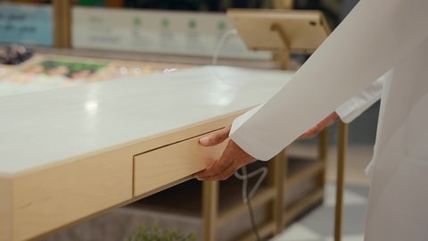 A closet full of sunglasses, the joy of shopping and buying by choosing suitable sunglasses, a close-up of the hands of an Emirati Gulf Arab man wearing a kandura choosing two sunglasses, having a good time, being confused about choosing suitable sunglasses