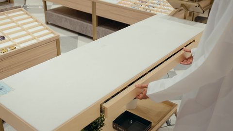 خزانه مليئه بالنظارات الشمسيه، متعة التسويق والشراء باختيار نظارة شمسية مناسبة، تصوير مقرب ليدين رجل عربي خليجي اماراتي يرتدي الكندوره يقوم باختيار نظارتان شمسيه، قضاء وقت ممتع، الحيرة في اختيار نظارة مناسبة