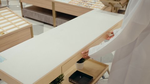 خزانه مليئه بالنظارات الشمسيه، متعة التسويق والشراء باختيار نظارة شمسية مناسبة، تصوير مقرب ليدين رجل عربي خليجي اماراتي يرتدي الكندوره يقوم باختيار نظارتان شمسيه، قضاء وقت ممتع، الحيرة في اختيار نظارة مناسبة