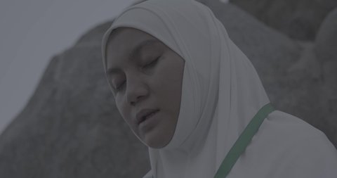 Pilgrims stand on Mount Arafat in the Kingdom of Saudi Arabia. A close-up of a pilgrim praying and turning to God Almighty on Mount Arafat. Reverence and the great feelings of Islamic faith. Performing the duties of Islam in Mecca. Completing the Hajj rituals.