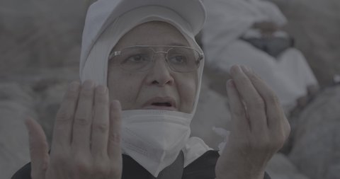Pilgrims stand on Mount Arafat in the Kingdom of Saudi Arabia. A close-up of a pilgrim praying and turning to God Almighty on Mount Arafat. Reverence and the great feelings of Islamic faith. Performing the duties of Islam in Mecca. Completing the Hajj rituals.
