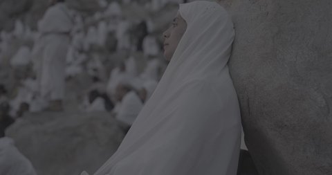 Pilgrims stand on Mount Arafat in the Kingdom of Saudi Arabia. A close-up of a pilgrim praying and turning to God Almighty on Mount Arafat. Reverence and the great feelings of Islamic faith. Performing the duties of Islam in Mecca. Completing the Hajj rituals.  Pilgrim, man, close-up
