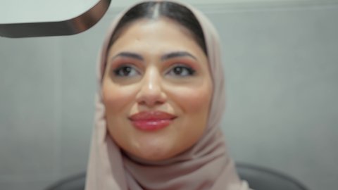 استخدام الأجهزة الحديثة المتطورة، تقييم الرؤية والكشف عن أمراض العيون للمريض،تصوير مقرب لامراة عربيه خليجيه اماراتية ترتدي العباءه الملونه في عيادة مختصة لفحص العيون تنظر من خلال مجموعة من العدسات ،مفهوم الخدمات والرعاية الصحية في المستشفيات والمراكز