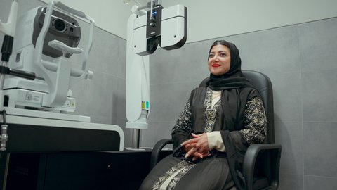 استخدام الأجهزة الحديثة المتطورة، تقييم مدى الرؤية والكشف عن الامراض العينية، مفهوم الخدمات والرعاية الصحية في المستشفيات والمراكز، تشخيص وتحديد المشاكل البصرية، تصوير مقرب لامراة عربية خليجية اماراتية ترتدي العباءة امام جهاز فحص العين للتأكد من صحة البصر