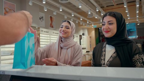 متابعة آخر صيحات الموضة والجمال, تسوق وشراء أحدث منتجات النظارات العصرية الحديثة, صديقتان عربيان خليجيان اماراتيان في متجر النظارات الشمسيه, امراة اماراتيه تقوم بالدفع الالكتروني، تطبيقات الهاتف للدفع عبر الانترنت، استخدام الاجهزه الحديثه