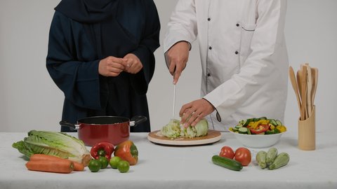 وصفات الطعام الشهية، مفهوم النظام الغذائي، الاستمتاع بالعمل الجماعي في مهنة الطبخ، أدوات خاصة بالمطبخ، تعلم وتطبيق فنون الطهي، تصوير مقرب ليد رجل وامرأة عربيين خليجيين اماراتيان يتشاركان في تجهيز الطعام، رجل خليجي يقوم  بتقطيع الخس لاعداد السلطه
