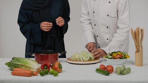 تحضير و إعداد الطعام، غذاء مفيد وصحي، الاستمتاع بالعمل الجماعي في مهنة الطبخ، أدوات خاصة بالمطبخ، تعلم وتطبيق فنون الطهي، تصوير مقرب ليد رجل وامرأة عربيين خليجيين اماراتيان يتشاركان في تجهيز الطعام، رجل خليجي يقوم  بتقطيع الخس لاعداد السلطه