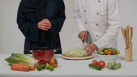 غذاء مفيد وصحي، تحضير و إعداد الطعام، الاستمتاع بالعمل الجماعي في مهنة الطبخ، أدوات خاصة بالمطبخ، تعلم وتطبيق فنون الطهي، تصوير مقرب ليد رجل وامرأة عربيين خليجيين اماراتيان يتشاركان في تجهيز الطعام، رجل خليجي يقوم  بتقطيع الخس لاعداد السلطه