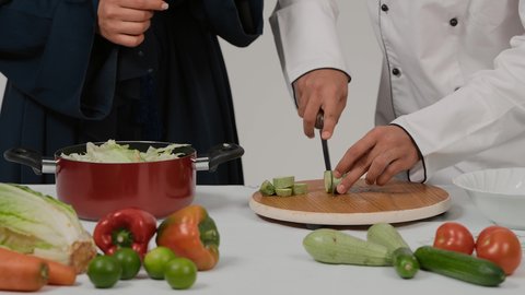 المشاركة بالأعمال المنزلية ومهارات الطبخ، أدوات خاصة بالمطبخ، تعلم وتطبيق فنون الطهي، تصوير مقرب ليد رجل وامرأة عربيين خليجيين اماراتيان يتشاركان في تجهيز الطعام، رجل خليجي يقوم بتقطيع الكوسة