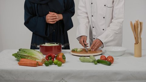 المشاركة بالأعمال المنزلية ومهارات الطبخ، أدوات خاصة بالمطبخ، تعلم وتطبيق فنون الطهي، تصوير مقرب ليد رجل وامرأة عربيين خليجيين اماراتيان يتشاركان في تجهيز الطعام، رجل خليجي يقوم بتقطيع الكوسة