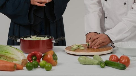 أدوات خاصة بالمطبخ، تعلم وتطبيق فنون الطهي، المشاركة في تحضير الوصفات الشهية، تصوير مقرب ليد رجل وامرأة عربيين خليجيين اماراتيان يتشاركان في تجهيز الطعام، رجل خليجي يقوم بتقطيع الكوسة