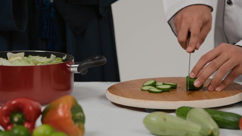 اعداد السلطة والأطباق الصحية، تعلم وتطبيق فنون الطهي، المشاركة في تحضير الوصفات الشهية، تصوير مقرب ليد رجل وامرأة عربيين خليجيين اماراتيان يتشاركان في تجهيز الطعام، رجل خليجي يقوم بتقطيع الخيارلاعداد السلطة