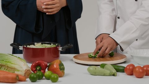 الاستمتاع بالعمل الجماعي في مهنة الطبخ، تجهيز مكونات السلطات والاطباق الصحية، تعلم وتطبيق فنون الطهي، المشاركة في تحضير الوصفات الشهية، تصوير مقرب ليد رجل وامرأة عربيين خليجيين اماراتيان يتشاركان في تجهيز الطعام، رجل خليجي يقوم بتقطيع الخيارلاعداد السلطة