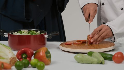 المشاركة في تحضير الوصفات الشهية، الاستمتاع بالعمل الجماعي في مهنة الطبخ، تصوير مقرب ليد رجل وامرأة عربيين خليجيين اماراتيان يتشاركان في تجهيز الطعام، رجل خليجي يقوم بتقطيع الطماطم لاعداد السلطة