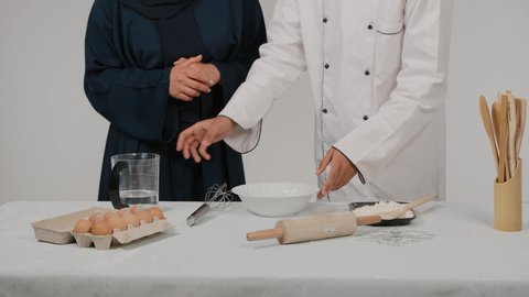 المشاركة في تحضير الوصفات الشهية، إعداد المخبوزات والمعجنات الشهية، الاستمتاع بالعمل الجماعي في مهنة الطبخ، تصوير مقرب ليد رجل وامرأة عربيين خليجيين اماراتيان يتشاركان في تجهيز الطعام، رجل خليجي يقوم بسكب المياه في الوعاء لاعداد الطعام